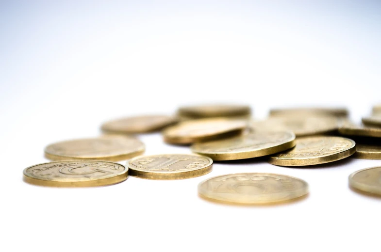 a pile of coins sitting on top of a table, a macro photograph, pexels, minimalism, set against a white background, istockphoto, dividing it into nine quarters, gilt metal