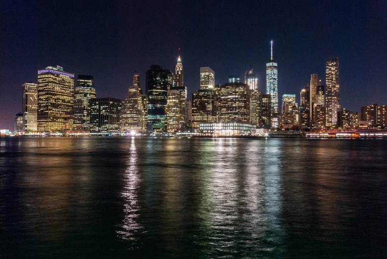 a view of a city at night from the water, by Joseph Pisani, 8k 50mm iso 10, panorama, gotham, slightly golden