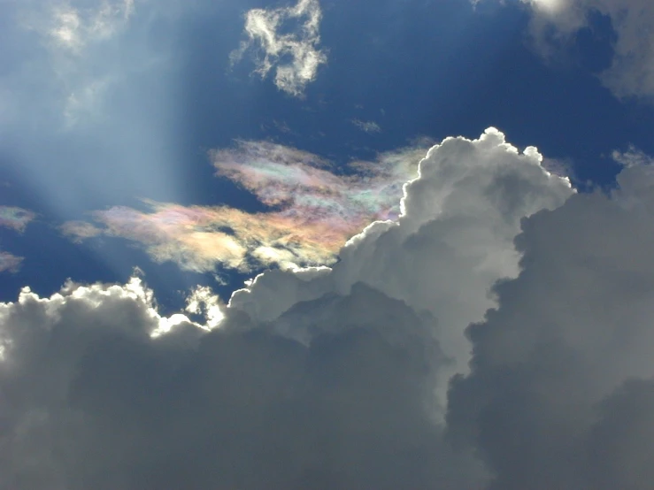 a plane flying through a cloudy blue sky, a photo, inspired by Frederic Church, hurufiyya, iridescent glistening smoke, in the astral plane ) ) ), ceremonial clouds, iridescence reflecting