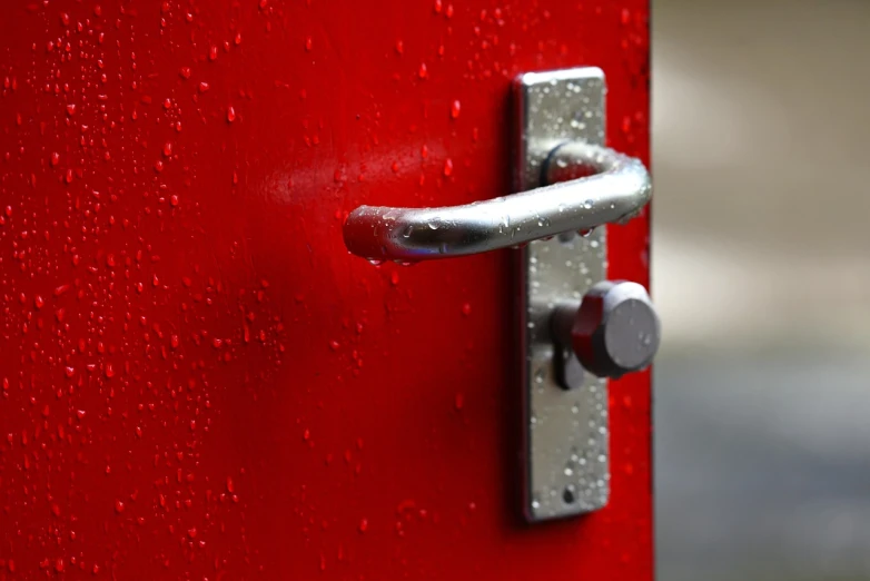 a close up of a door handle on a red door, a stock photo, by Edward Corbett, unsplash, wet from rain, aluminum, open portal to another dimension, museum quality photo