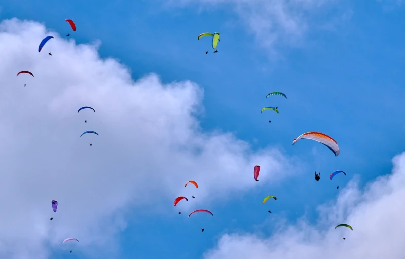 a group of people flying kites in the sky, a picture, figuration libre, skydiving, today\'s featured photograph 4k, under blue clouds, 1128x191 resolution