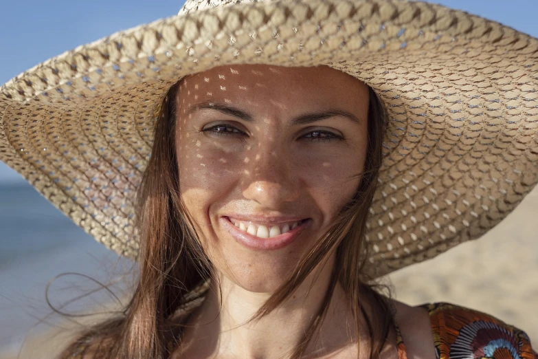 a woman wearing a straw hat on the beach, a portrait, stunning closeupheadshot, avatar image, bottom angle, smiling