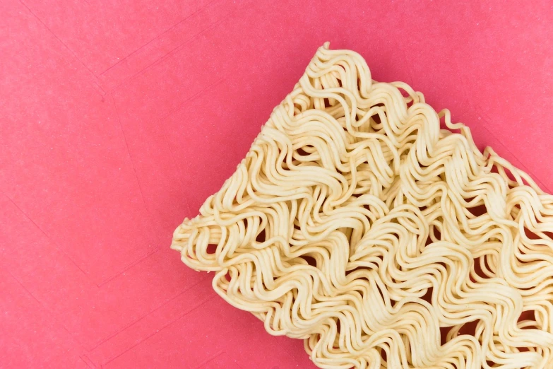 a pile of noodles sitting on top of a pink surface, modernism, crisp photo, weave, high detail product photo