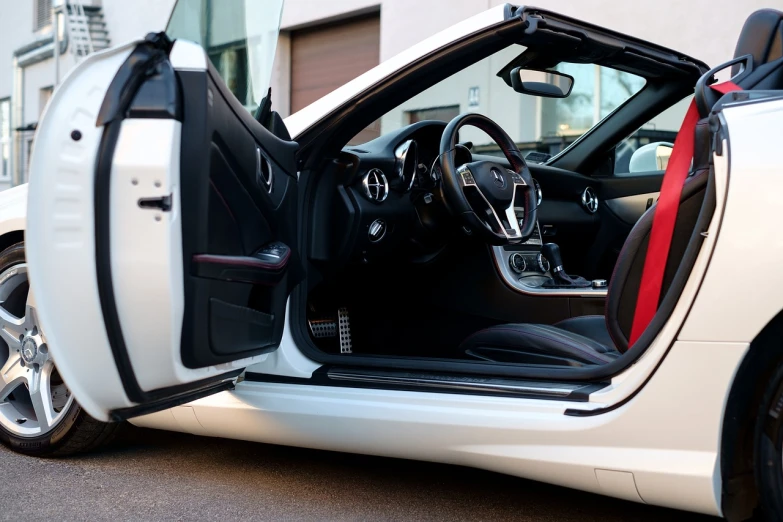 a white sports car parked in front of a building, a portrait, by Thomas Häfner, shutterstock, red leather interior, open door, interior of a small, full body close-up shot