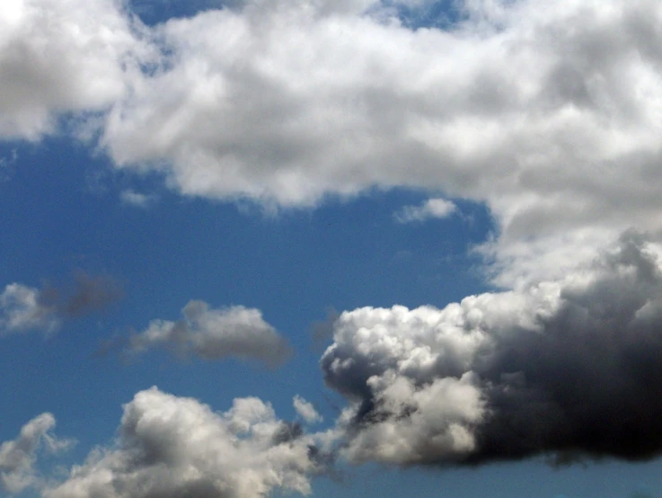 a jetliner flying through a cloudy blue sky, a photo, flickr, precisionism, towering cumulonimbus clouds, loosely cropped, (smoke), black clouds