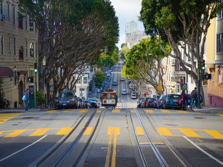 a street filled with lots of traffic next to tall buildings, by Douglas Shuler, shutterstock, san francisco, street tram, massive trees with warm windows, unsplash contest winning photo