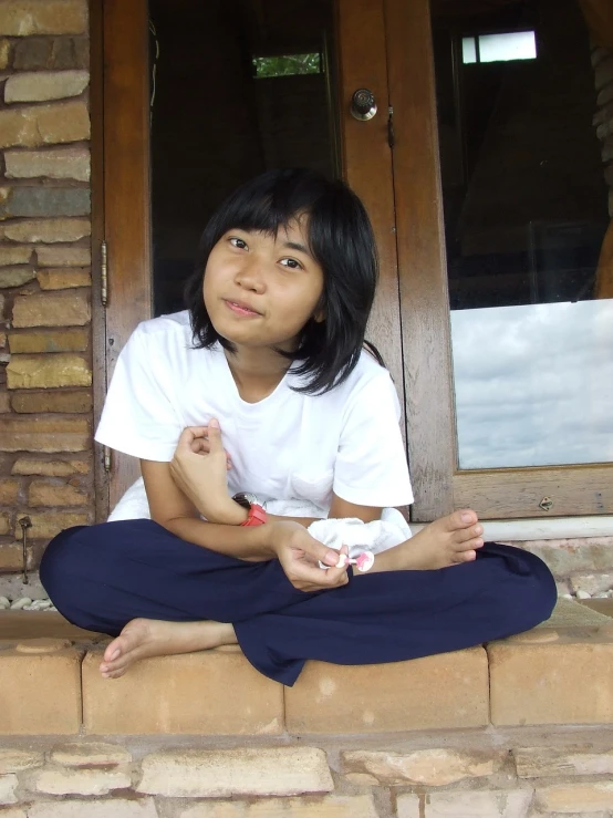 a young girl sitting on the steps of a house, a picture, inspired by I Ketut Soki, flickr, young cute wan asian face, teen, sitting on a table, cute:2