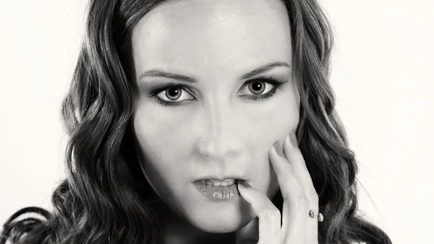 a black and white photo of a woman holding her hand to her face, a black and white photo, inspired by Peter Basch, photorealism, beckinsale, piercing stare, color studio portrait, action glamour pose