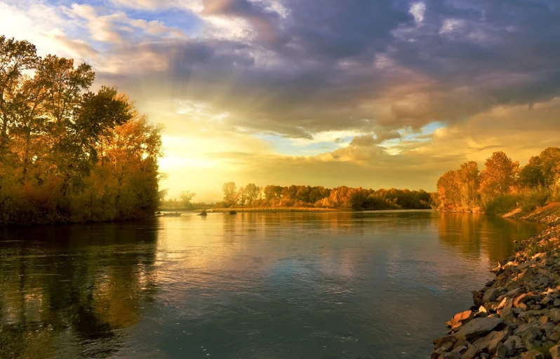 a large body of water next to a forest, a picture, romanticism, rays of golden sunlight, scenic view of river, autumn sunset, rivers