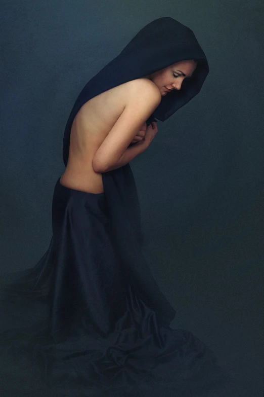 a woman in a black dress with a hood over her head, a photo, by Maciej Kuciara, figurative art, bare back, dark blue, studio photoshot, retouched in photoshop