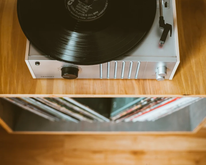 a record player sitting on top of a wooden table, an album cover, unsplash, stock photo, rack focus, scratched photo, with a long white