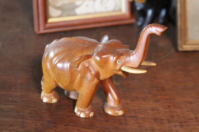 a close up of a figurine of an elephant on a table, by Harold Elliott, flickr, hurufiyya, displayed on mahogany desk, wood ornaments, smooth shank, taken with canon 8 0 d