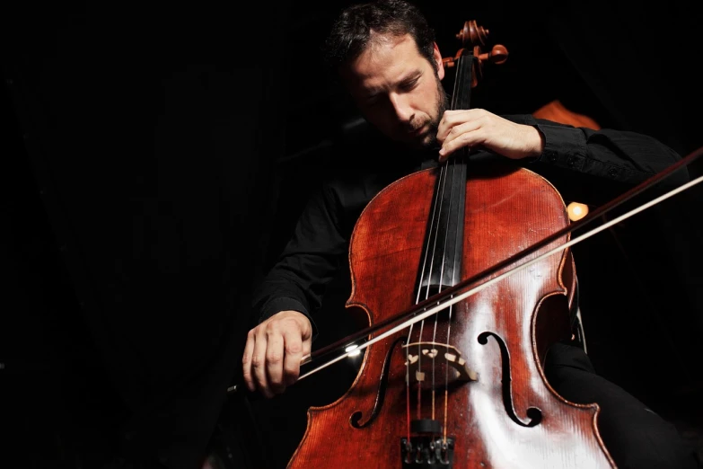 a man in a black shirt playing a cello, a portrait, by Matthias Weischer, shutterstock, concert photo, paul chadeisson, pulling strings, james zapata