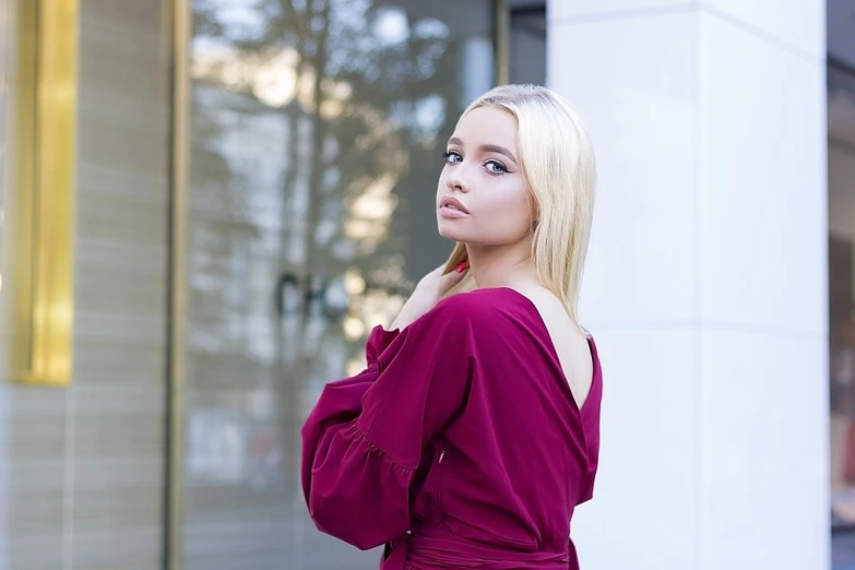 a woman in a red dress standing in front of a building, a portrait, instagram, realism, blonde beautiful young woman, ukrainian girl, long magenta haire, kailee mandel