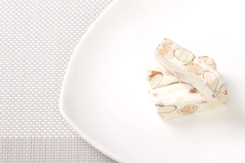 a piece of cake sitting on top of a white plate, a picture, by Shigeru Aoki, arabesque, close-up product photo, nut, white bones, product photo