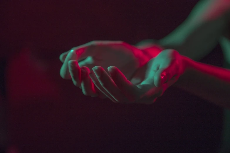 a close up of a person holding something in their hands, inspired by Elsa Bleda, aestheticism, red and green lighting, empty hands, dark blue and red, cyan and magenta