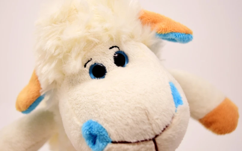 a close up of a stuffed animal on a white background, by Hans Schwarz, flickr, m & m plush, sheep, has two adorable blue eyes, warm and joyful atmosphere