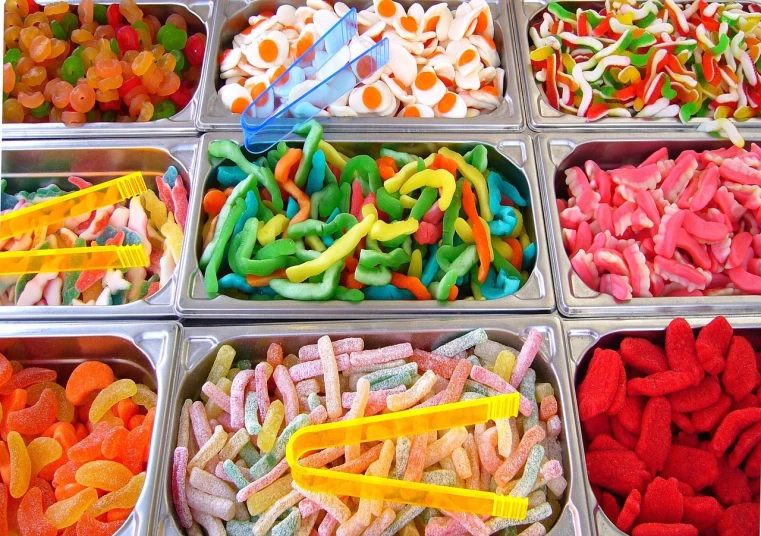 a display case filled with lots of different types of candies, tumblr, gummy worms, bright ”, in a row, food photography”