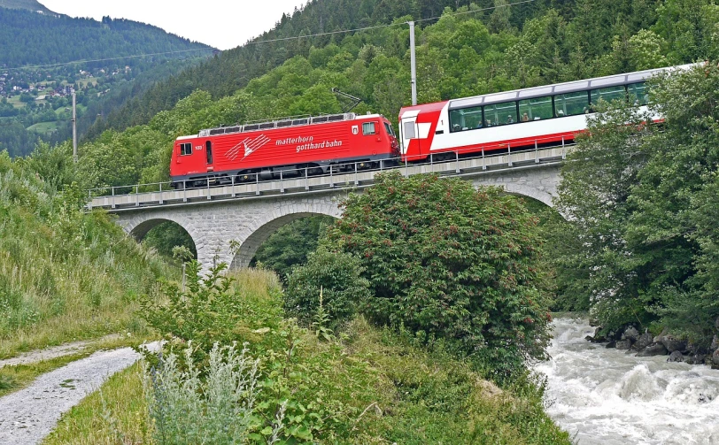 a red and white train traveling over a bridge, inspired by Jan Zrzavý, flickr, alps, a green, july, ox