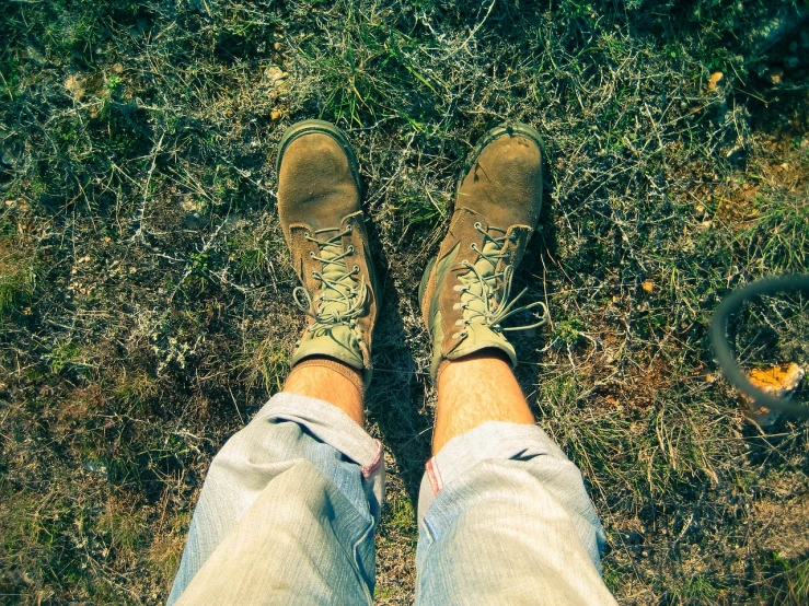 a person standing on top of a grass covered field, by Romain brook, detailed shot legs-up, green and brown tones, hiking clothes, postprocessed)