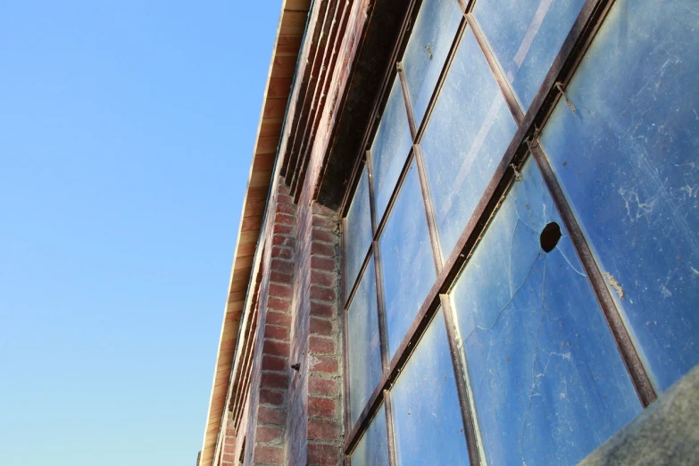 a clock that is on the side of a building, by Hannah Tompkins, modernism, abandoned factory, clear blue sky, glass window, detailed zoom photo