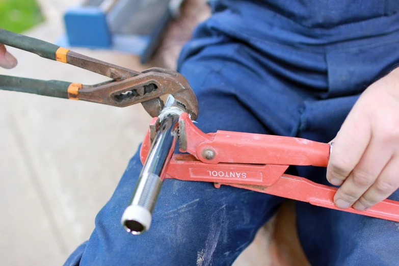 a close up of a person holding a pipe cutter, basic photo, hammers, zigor samaniego, under repairs