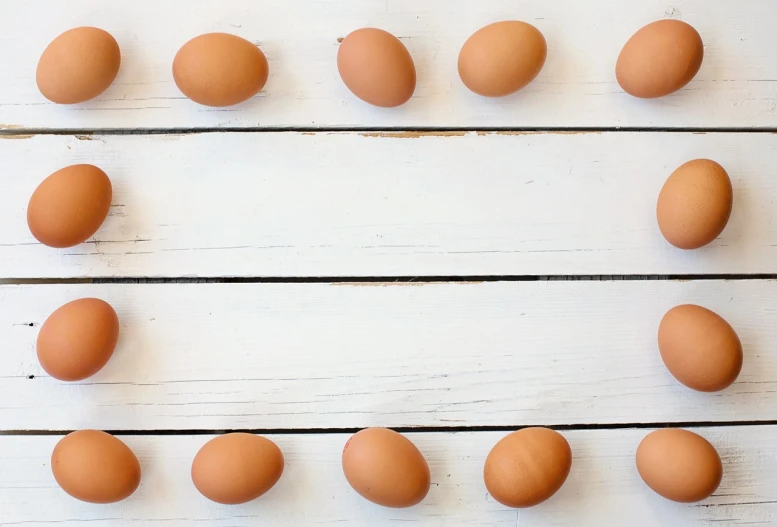 a number of brown eggs on a white table, a stock photo, fine art, background image, frame, hearts, rule for thirds