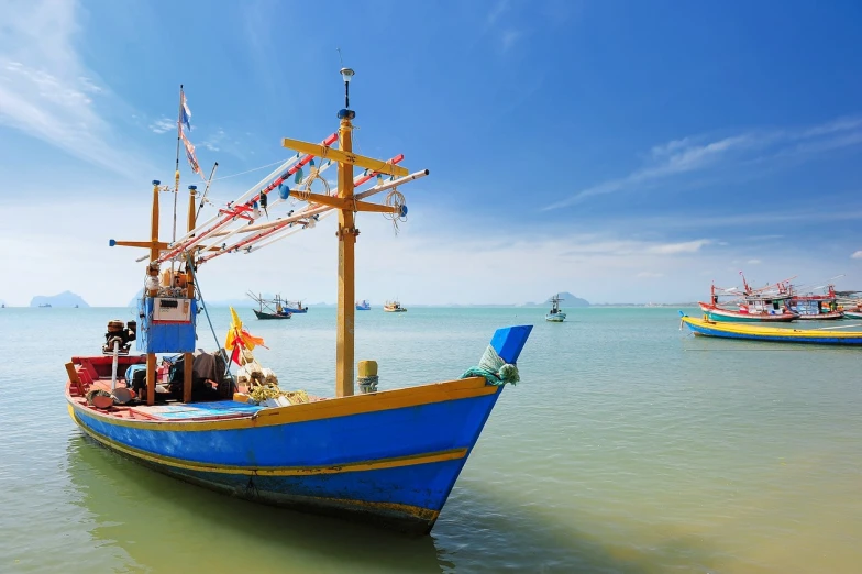 a blue boat sitting on top of a body of water, a picture, by Richard Carline, shutterstock, south east asian with long, fishing boats, on a bright day, celebrating