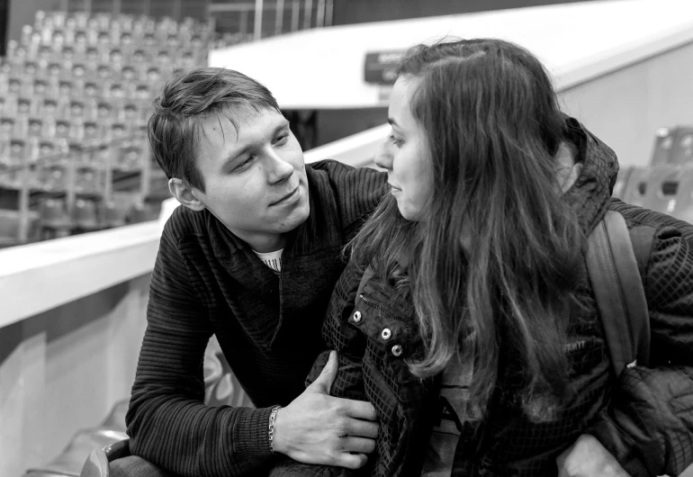 a man and a woman sitting next to each other, a black and white photo, by Maksimilijan Vanka, flickr, in an arena pit, making eye contact, daniil kudriavtsev, reassuring