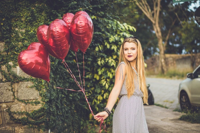 a woman holding a bunch of red balloons, inspired by Elsa Bleda, pexels, romanticism, dslr photo of a pretty teen girl, lush surroundings, several hearts, blonde beautiful young woman
