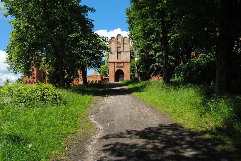 a dirt road with a clock tower in the background, by Jan Stanisławski, flickr, romanesque, huge gate, brick, sunny summer day, anato finnstark. front view