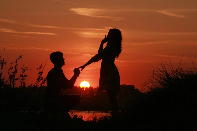a man holding a woman's hand in front of a sunset, a picture, tumblr, romanticism, kneeling, man proposing his girlfriend, singing, watch photo