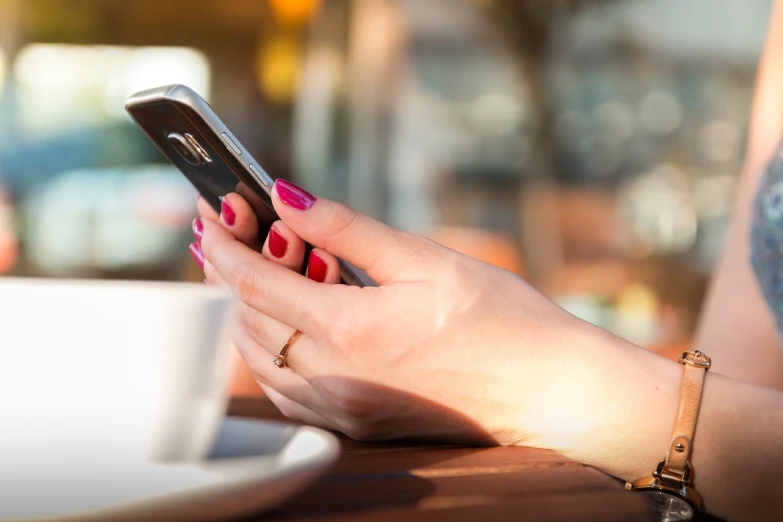 a close up of a person holding a cell phone, happening, morning coffee, manicured, slightly sunny, sitting down