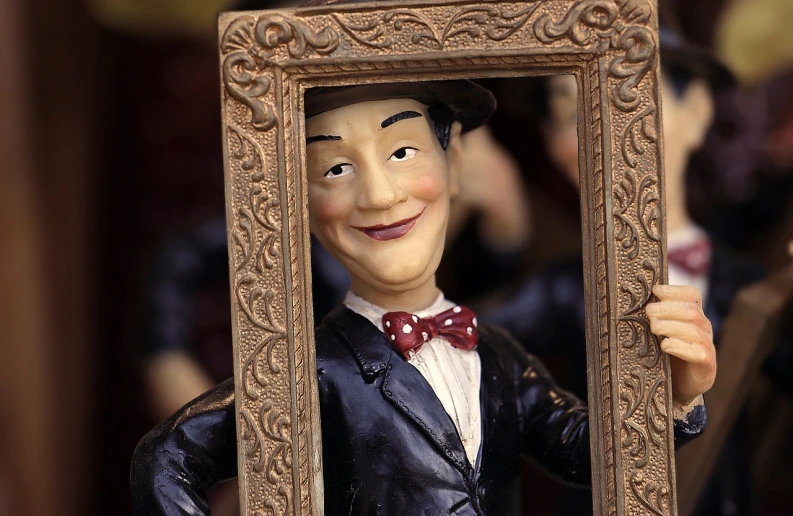 a statue of a man holding a picture frame, a picture, folk art, toy commercial photo, highly detailed photo of happy, attractive magician man, woo kim