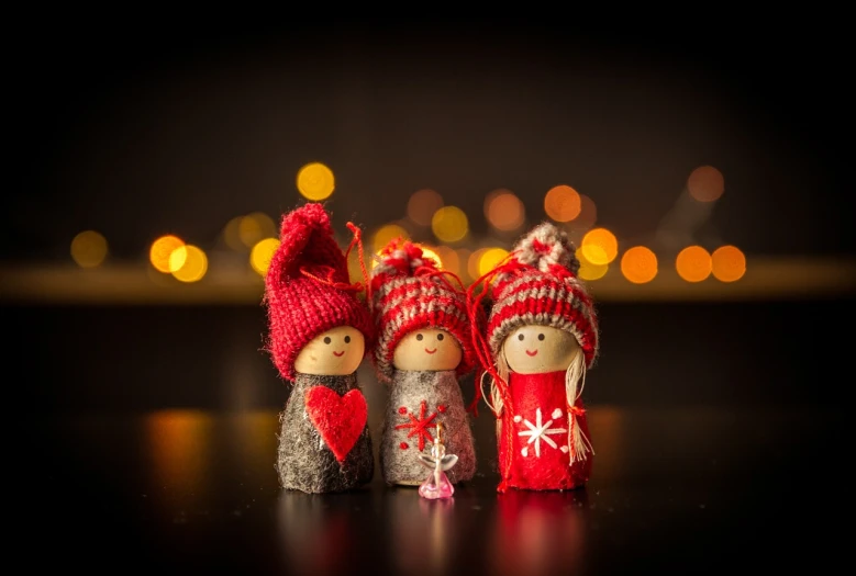 a couple of figurines sitting on top of a table, a picture, by Jesper Knudsen, pexels, folk art, christmas lights, 3 figures as winter spirits, reds, cute and lovely