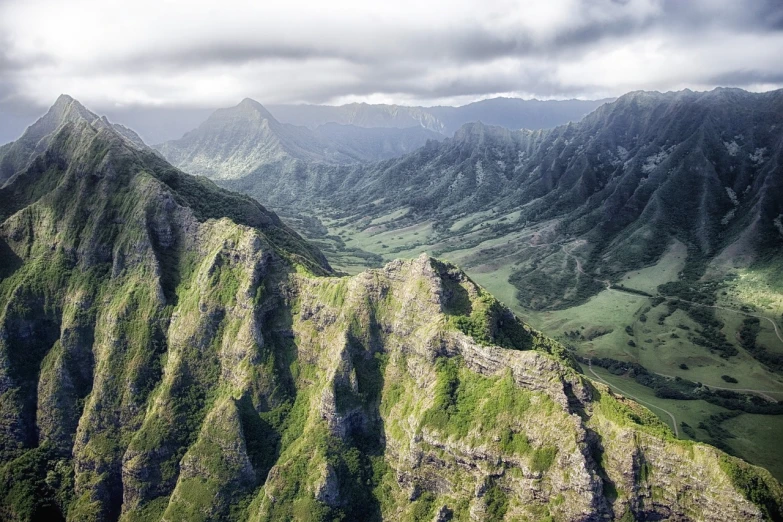 a view of a valley with mountains in the background, a detailed matte painting, pexels, hawaii, aerial shot from the drone, istock, sharp cliffs