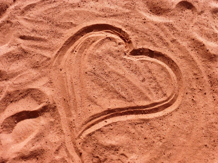 a heart drawn in the sand on a beach, a photo, inspired by János Valentiny, land art, red sandstone natural sculptures, etched relief, iphone wallpaper, family friendly