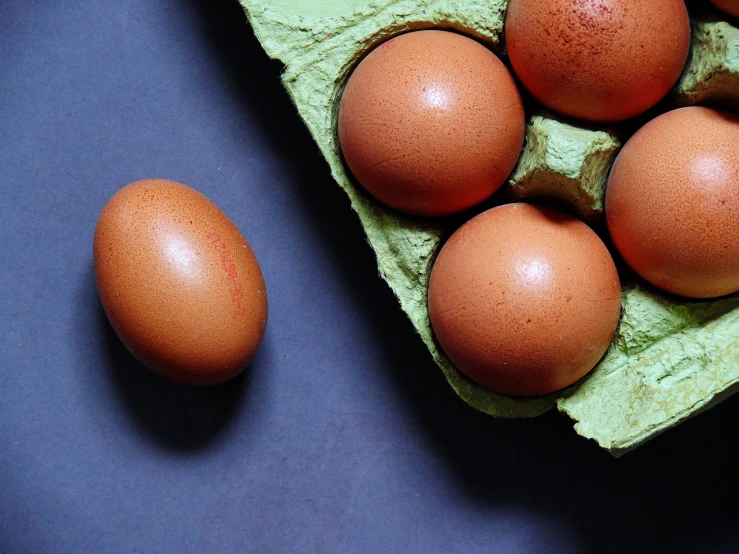 a carton of eggs sitting on top of a table, a photo, by László Balogh, with a black background, a green, background image, half image