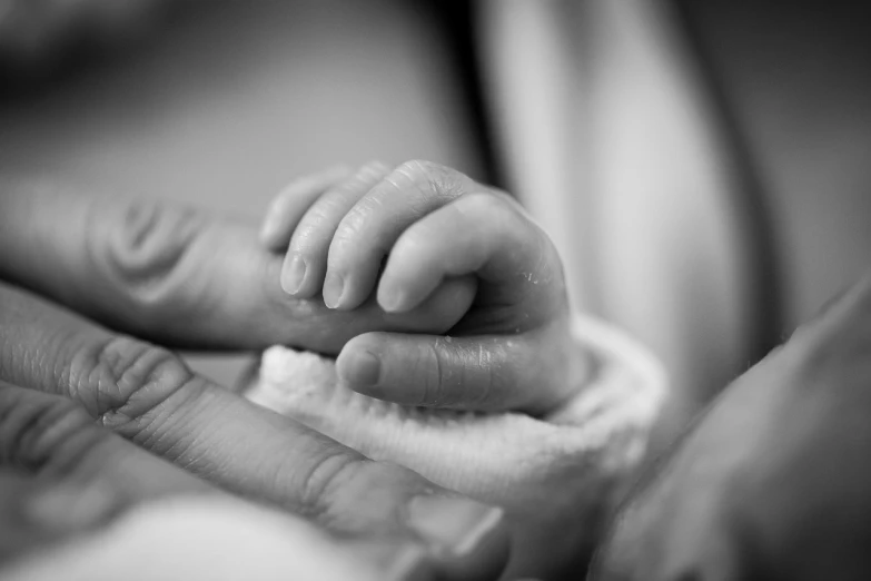 a close up of a person holding a baby's hand, a black and white photo, birth, serene expression, lots of light, 4 0 9 6