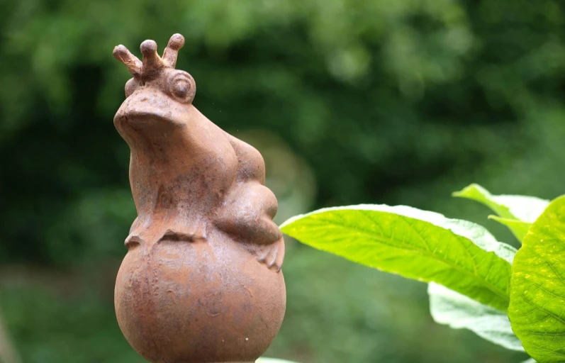 a statue of a frog sitting on top of a plant, inspired by Károly Patkó, flickr, new sculpture, happy wise. he has bouncy belly, rust, close - up profile, quirky king of faes ( with long