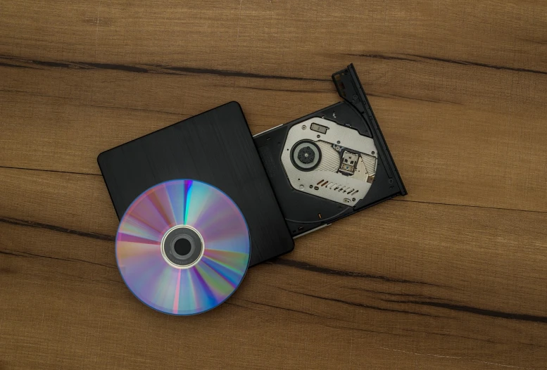 a compact disk sitting on top of a wooden table, a stock photo, computer art, miniature product photo, bad vhs, with a wooden stuff, high detail product photo