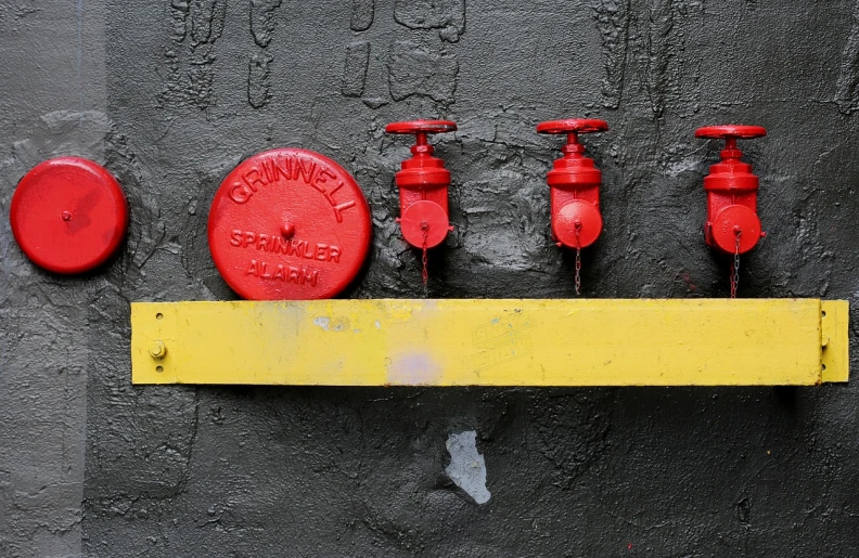 a red fire hydrant sitting on top of a yellow ruler, by Stefan Gierowski, flickr, street art, droplets on the walls, black steel with red trim, bells, in a row