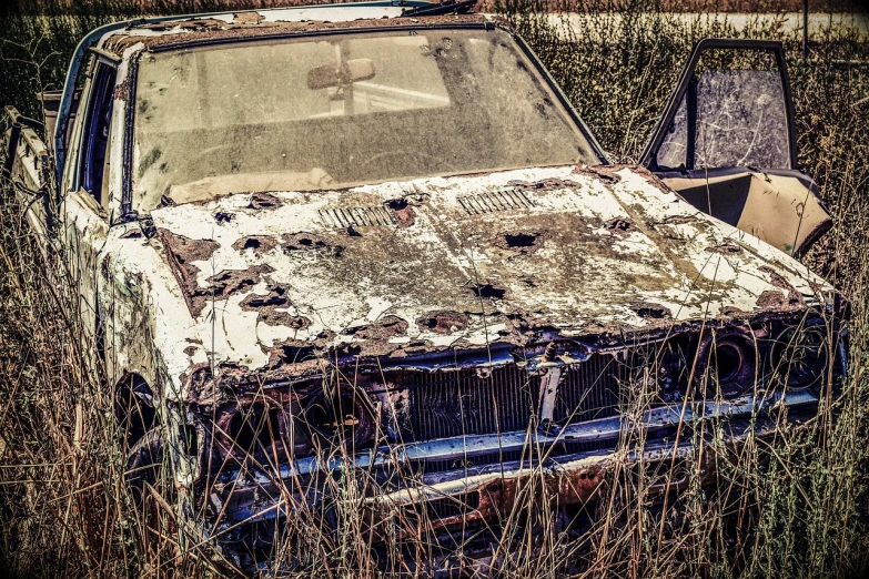 an old car that is sitting in the grass, a photo, by Richard Carline, auto-destructive art, texture of old rust and trash, phone photo, enhanced photo, harsh sunlight