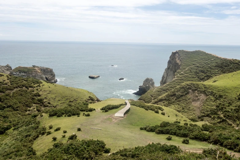 a view of the ocean from the top of a hill, mingei, curved bridge, wide shot photo, sharp cliffs, modern high sharpness photo