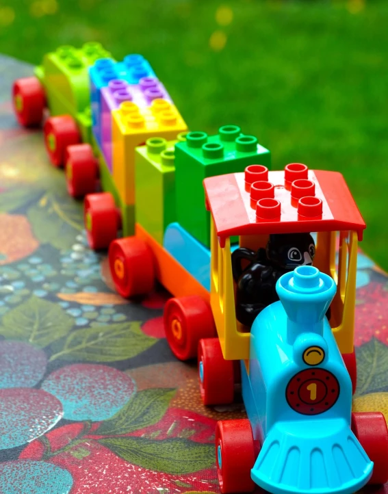 a close up of a toy train on a table, by Anna Haifisch, pexels contest winner, process art, colorful plastic, big engine, wimmelbilder maze made of lego, on a bright day