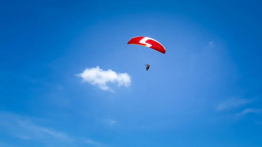 a person that is flying a kite in the sky, a stock photo, parachutes, blue and red, shot on nikon z9, bright sunny summer day