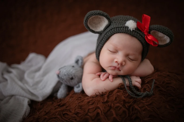 a baby sleeping next to a stuffed animal, inspired by Anne Geddes, shutterstock contest winner, mouse with drum, red brown and grey color scheme, candid portrait photo, it's wearing a cute little hat