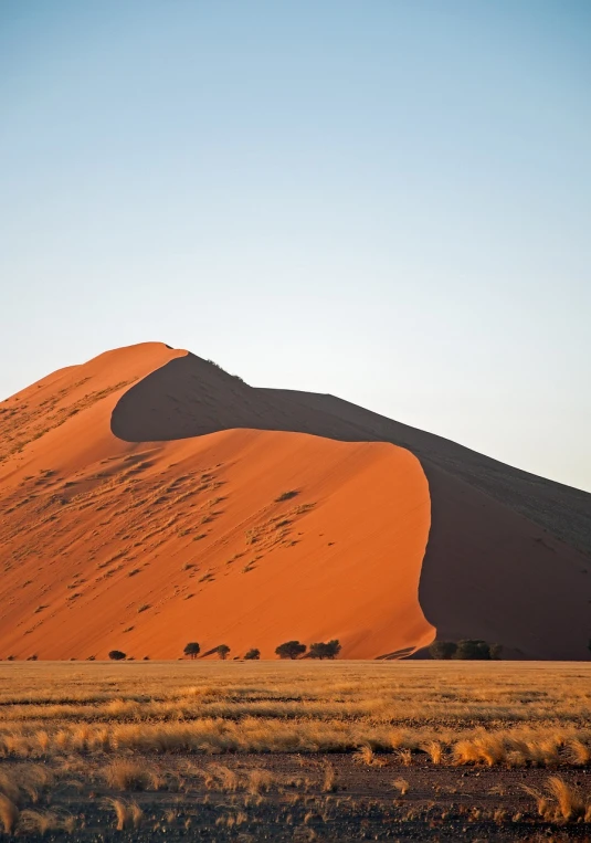 a large sand dune in the middle of a desert, by Peter Churcher, flickr, early morning light, that resembles a bull\'s, red hues, muzinabu