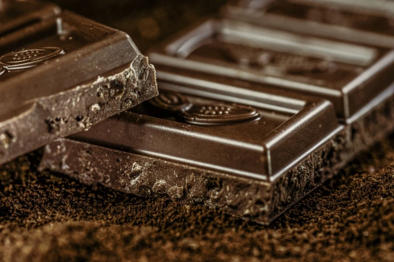 a couple of chocolate bars sitting on top of a pile of dirt, a portrait, by Aleksander Gierymski, shutterstock, dark shading, chocolate. intricate background, close up. macro. hyper realistic, drink
