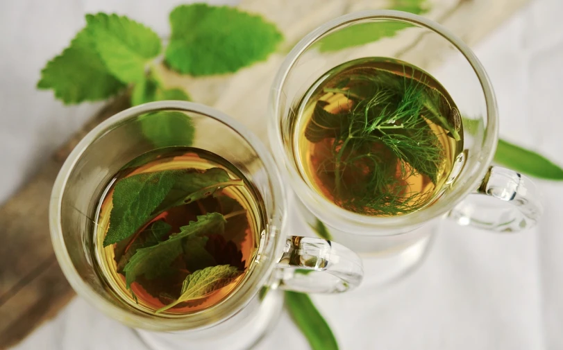 a couple of cups of tea sitting on top of a table, pixabay, renaissance, mint leaves, cooking oil, zoomed in, upside-down